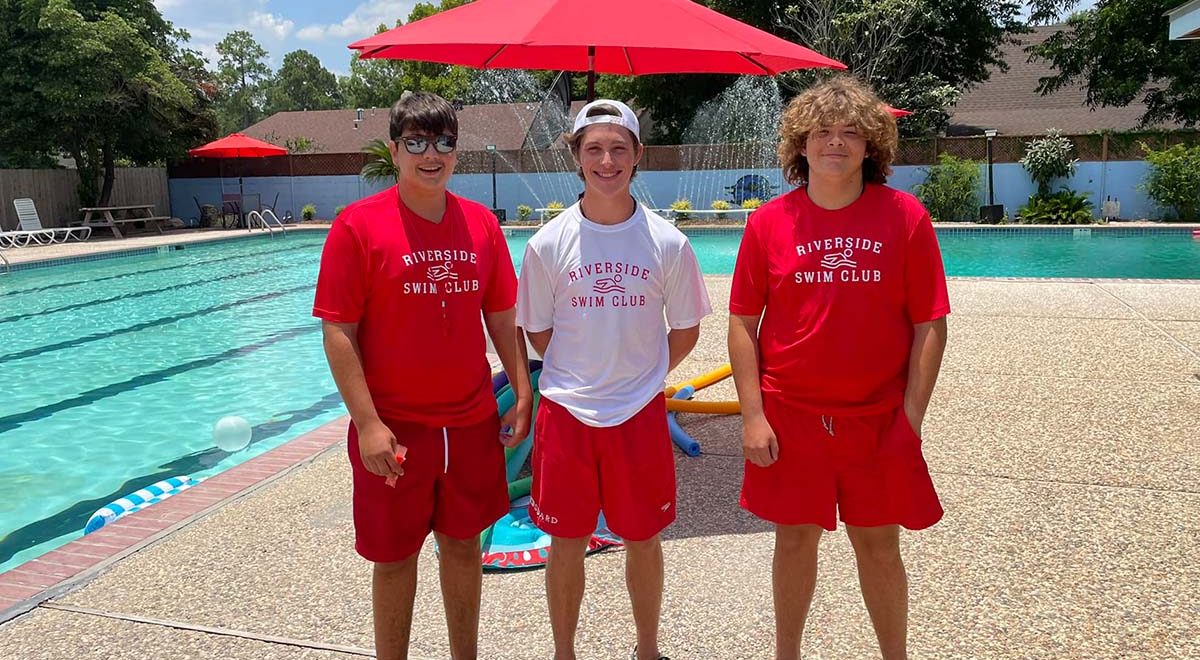Photo of 3 young lifeguards posing next to the pool at Riverside Swim Club,