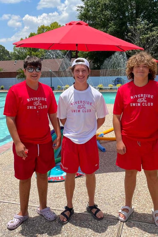 Photo of 3 young lifeguards posing next to the pool at Riverside Swim Club,